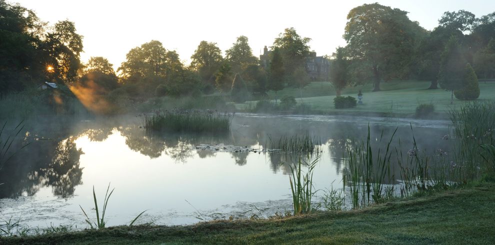 An image of the grounds of a country estate by a lake.