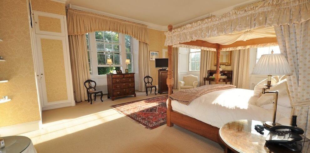 a large bedroom with four poster bed