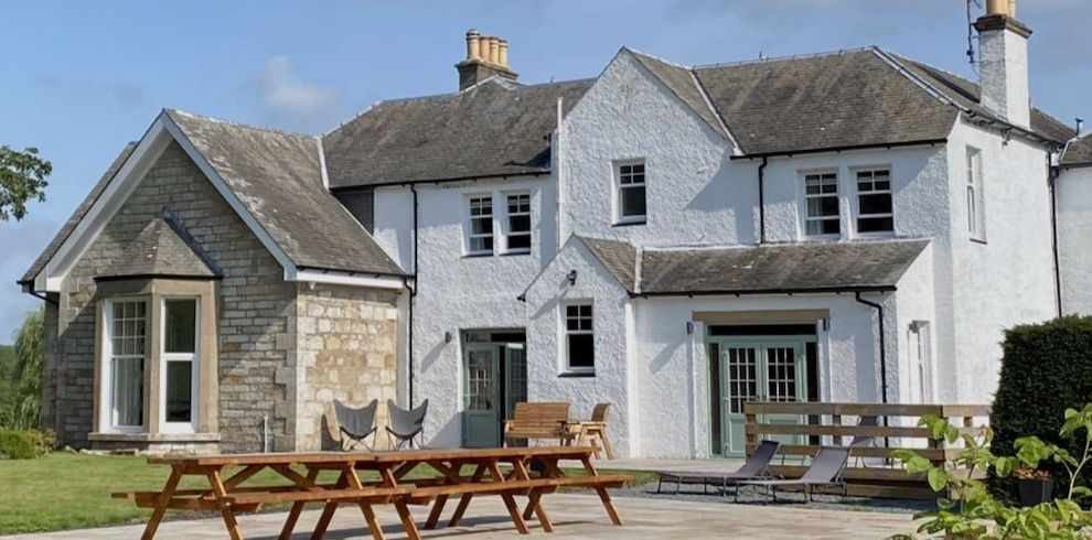 large white farmhouse with picnic benches