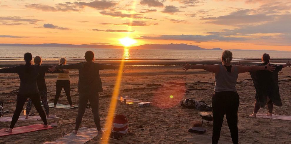 women doing yoga down the beach