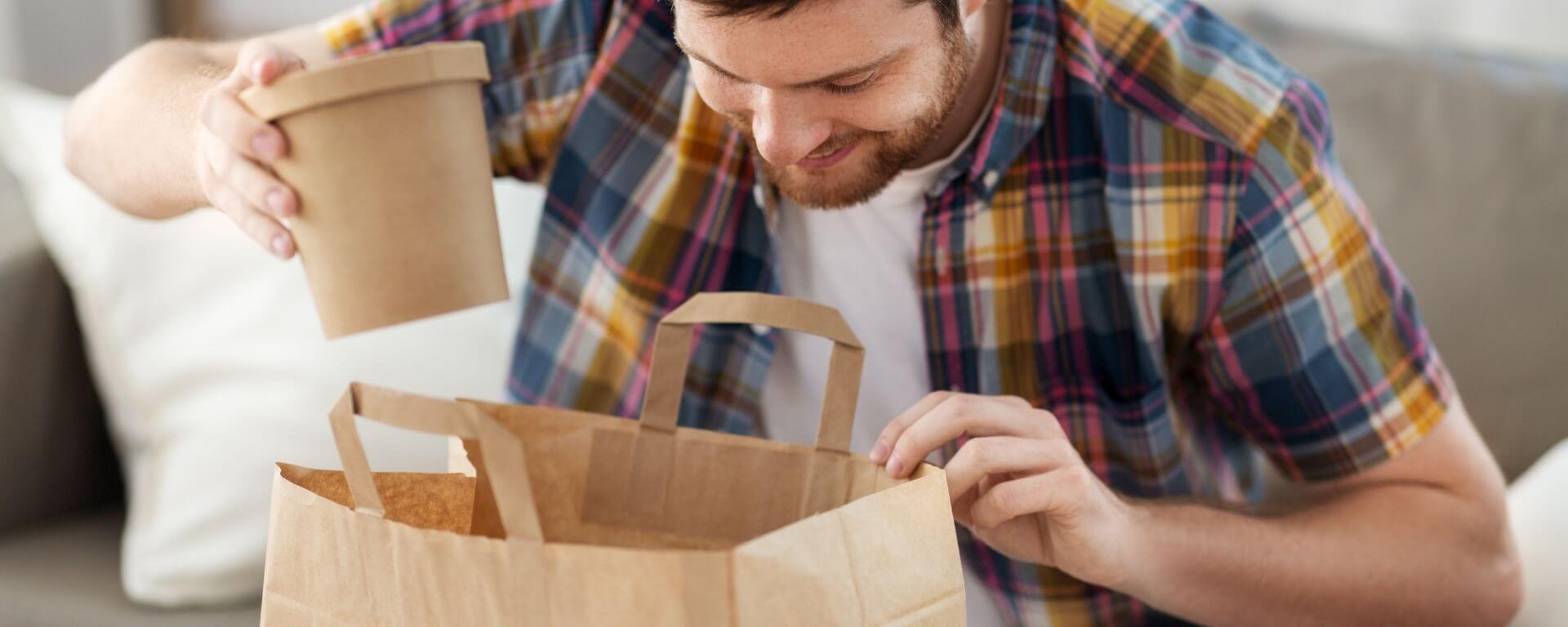 Person taking out food carton from paper bag.