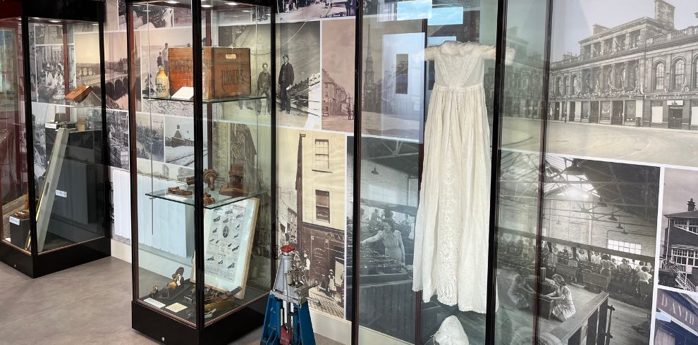 Glass cabinet with artefacts in front of a wall of old images.