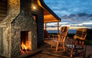 A fireplace next to a cabin with rocking chairs