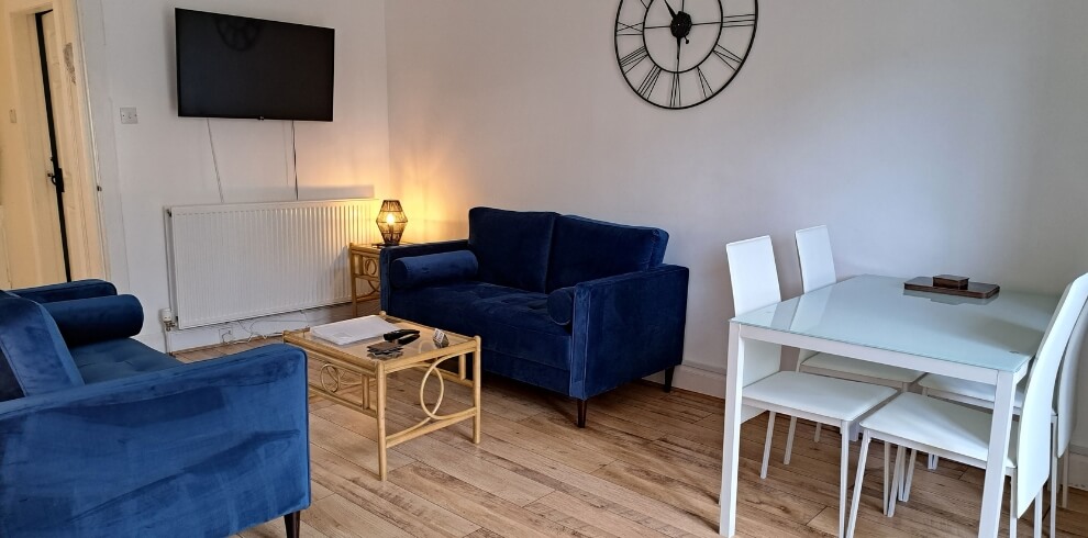 Small living room with blue couches and dining area.