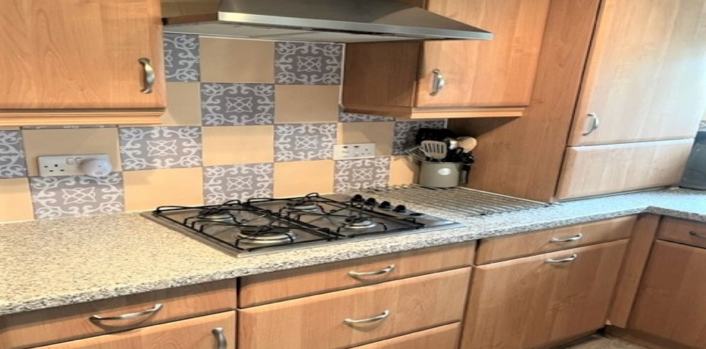 Kitchen area with gas hob and extractor fan with utentils on the counter top.