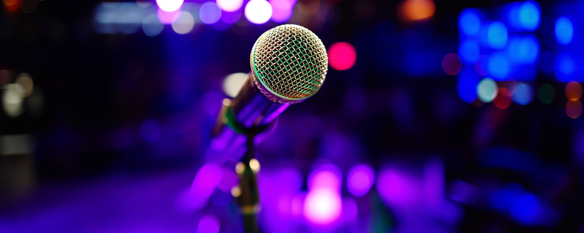 Microphone to the forefront purple lighted stage in background.