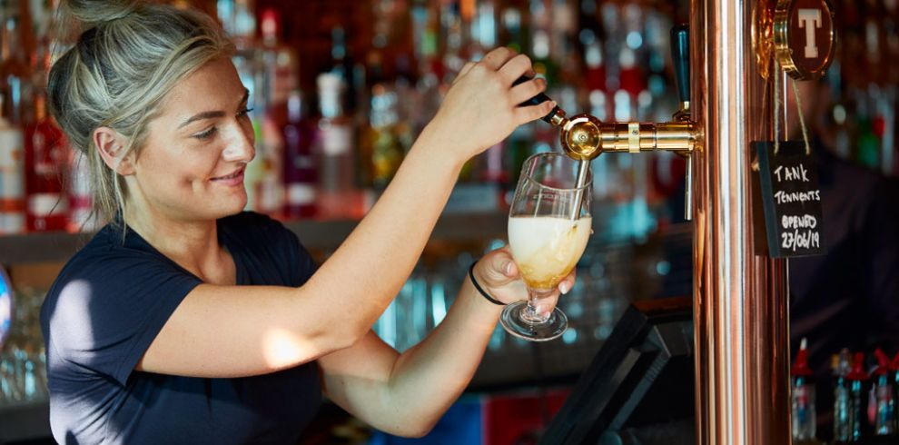 Person pulling a pint behind a bar.