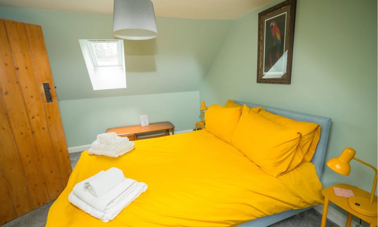 A Picture of a bedroom at Tig Cottage featuring a double bed and wooden wardrope.