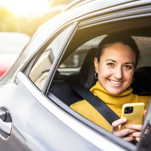 Woman with yellow jumper in the back seat of a car.