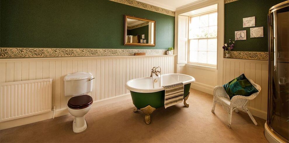 Green and white bath room with a roll top bath