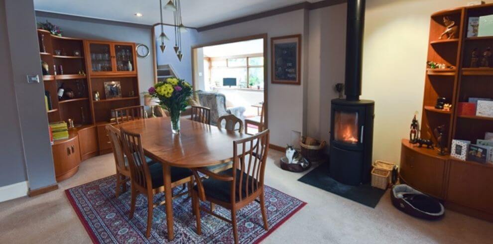 a room with a large dining table and woodburner