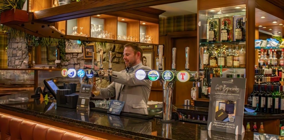 An image of a bar with the barman pulling a pint.