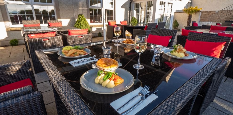 An image of a seated outdoor area. There is food on the table.