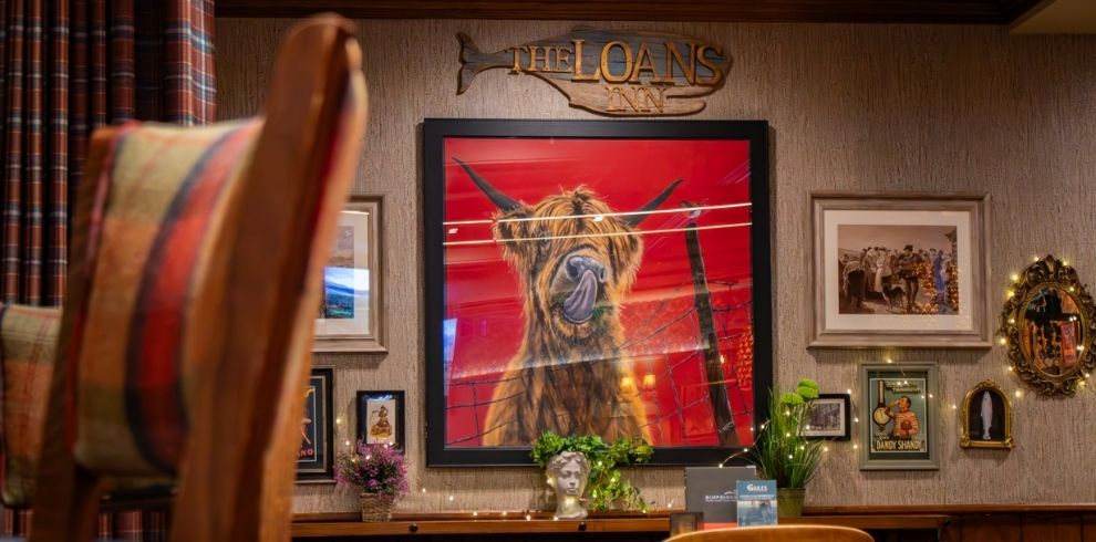 An image of Ddining area. There is a pictur eon the wall of a Highland cow.