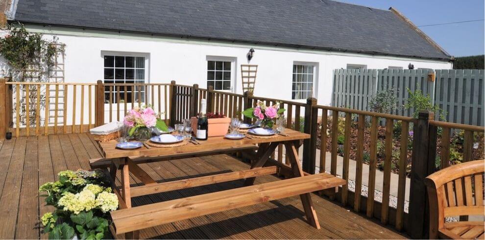 decking with picnic table with cottage in background
