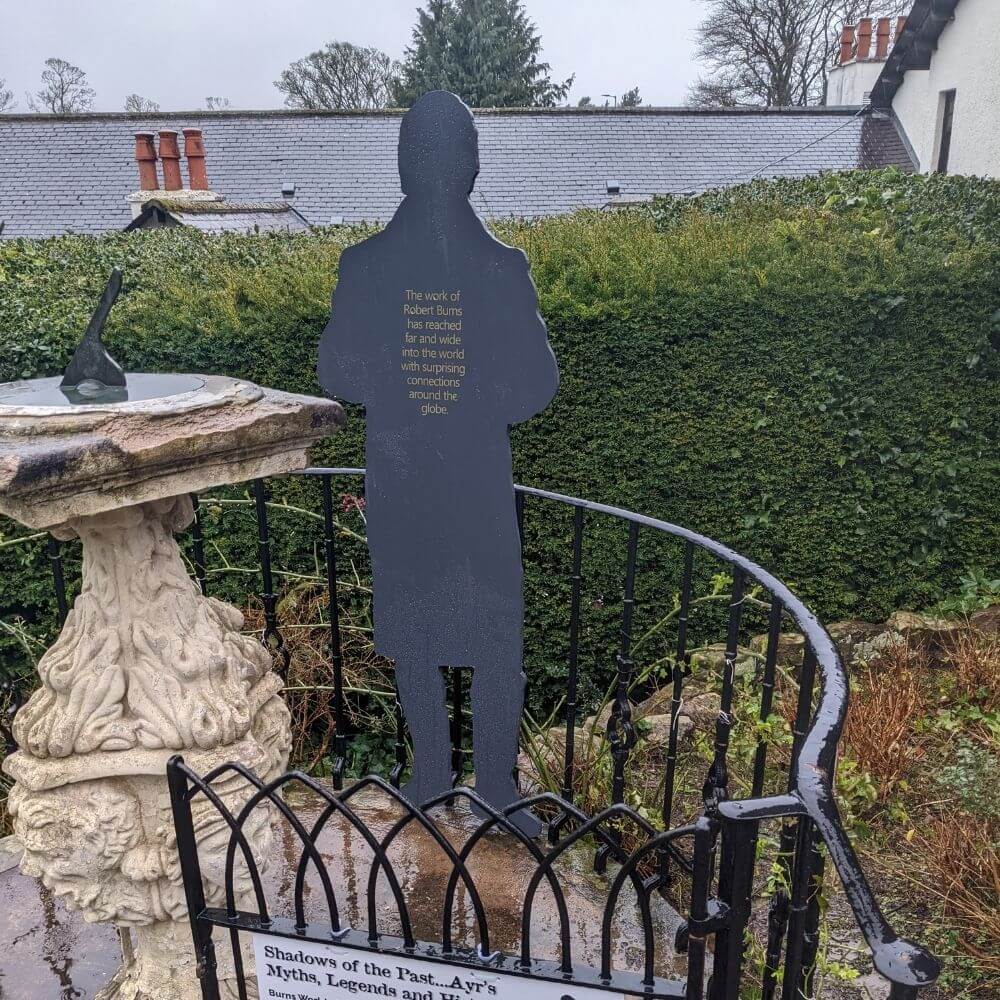 Wooden silhouette of Robert Burns in memorial garden.