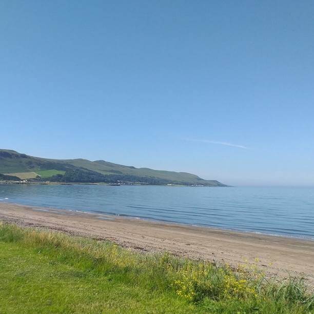 View of beach and coastline on beautiful sunny day with clear blue skies.