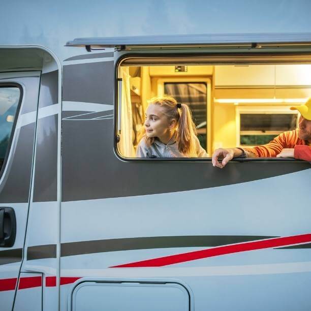 Girl and man looking out the window of a campervan.