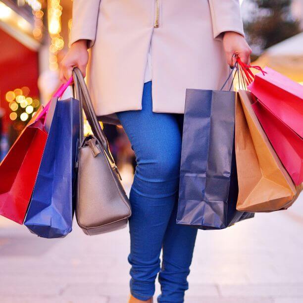 Person carrying colourful shopping bags.