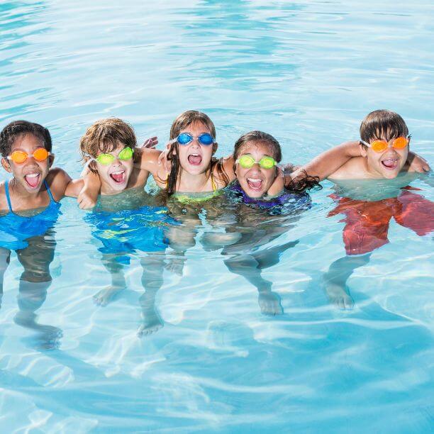 Group of children wearing goggles in a swimming pool.