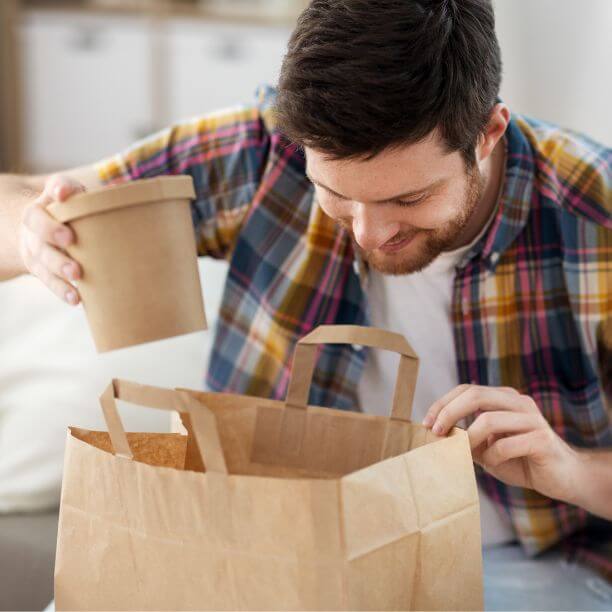 Person taking out food carton from paper bag.