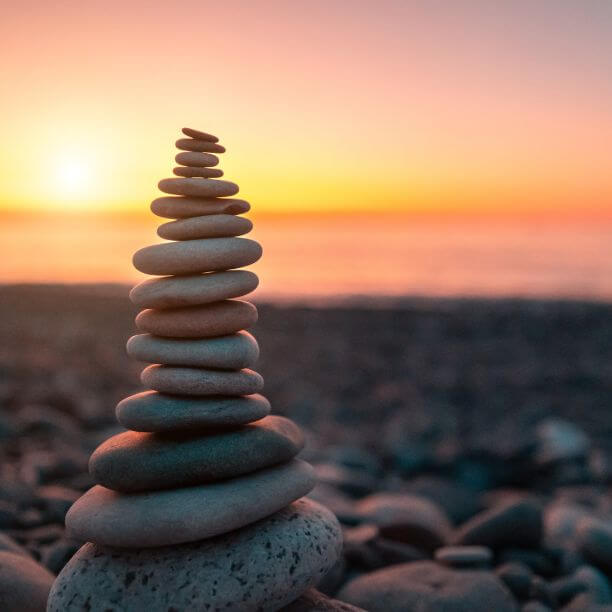 Stone pile on a beach with sunset in background.