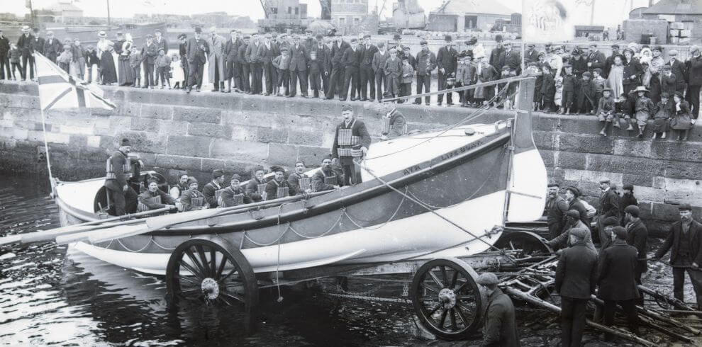 Old black and white photograph of a small boat being launched.