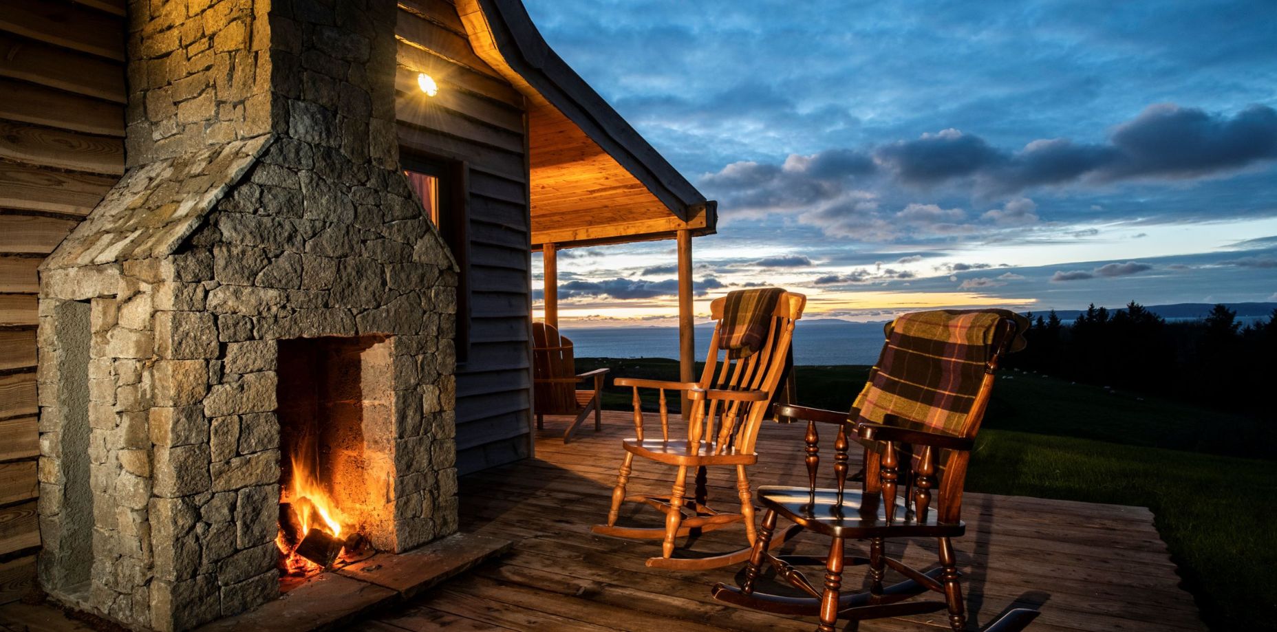 A fireplace next to a cabin with rocking chairs
