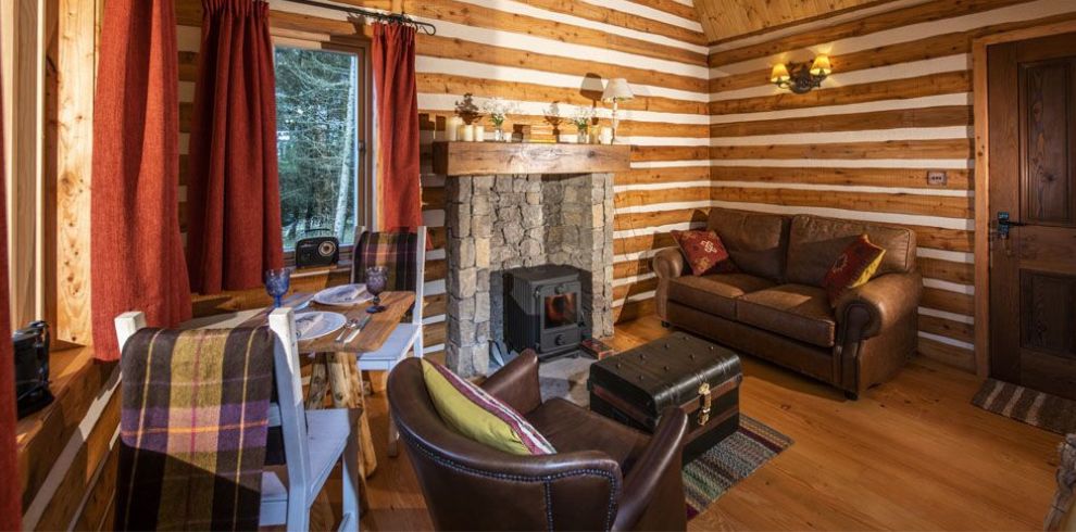Cabins living room with fireplace looking at a window at one side and a door on the other