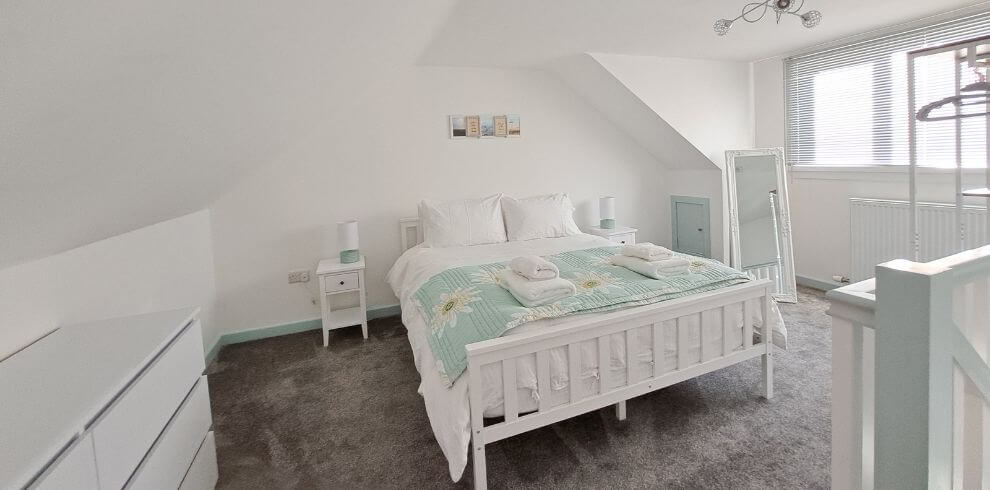Fresh white bedroom with pastel coloured bedding.