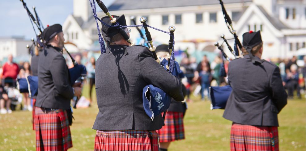 Group of men playing the bagpipes at an outdoor event.
