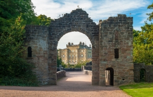 Stone castle gateway with a view of castle in the distance.