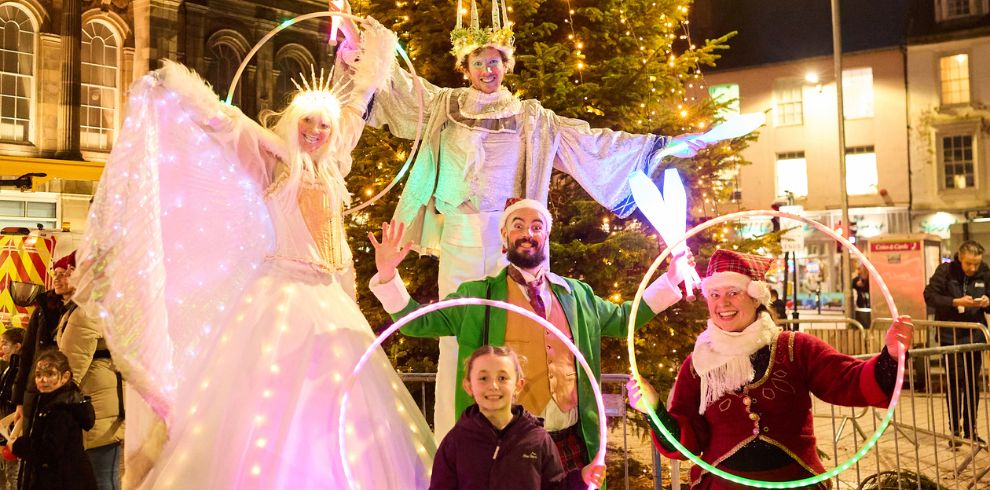 Merry makers in costumes play with hula hoops at Christmas fest.