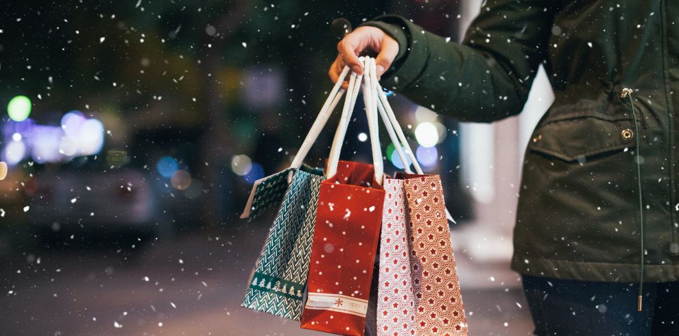 Hand holding bags of Christmas shopping.