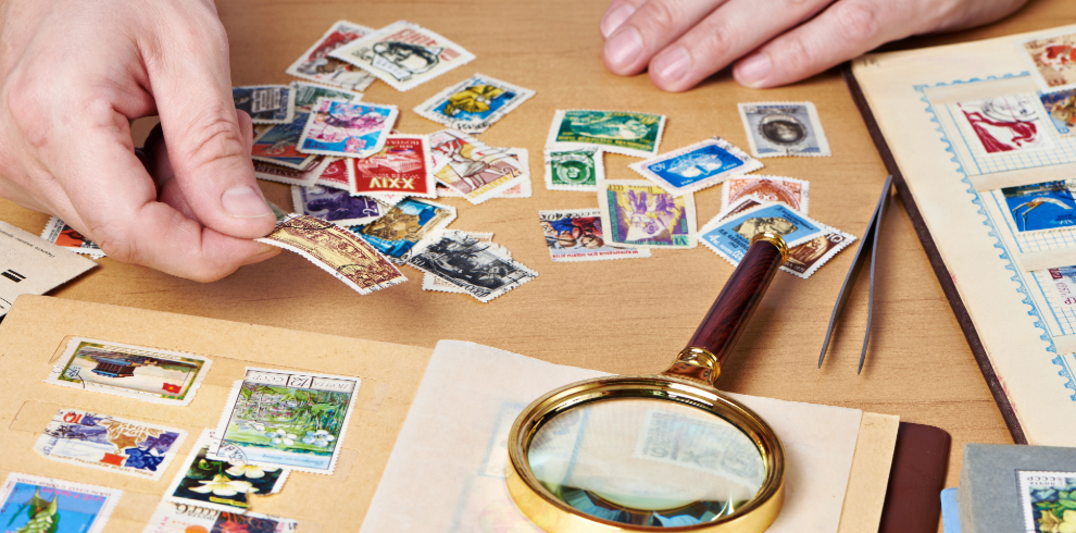 An image of stamps placed on a table and a magnifying glass.
