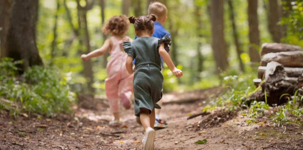 Young children running on a woodland path.