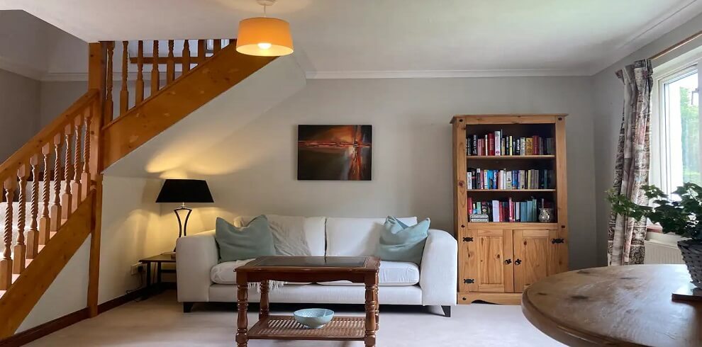 Living and dining area of Skye Cottage. Images features a white sofa, book caske, coffee table.