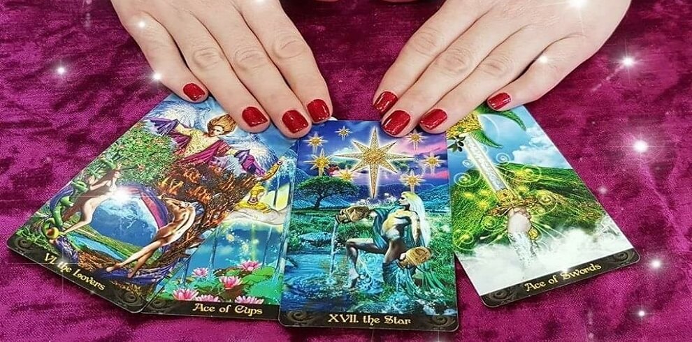 An image shows tarot cards spread out on a burgundy velvet table. A pair of hands, with nails painted in red nail varnish, hovers over the cards as if preparing for a reading.