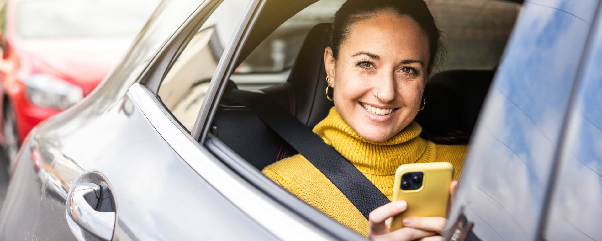 Woman with yellow jumper in the back seat of a car.