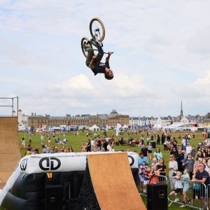 Person doing a stunt on a bmx bike in front of a large crowd.