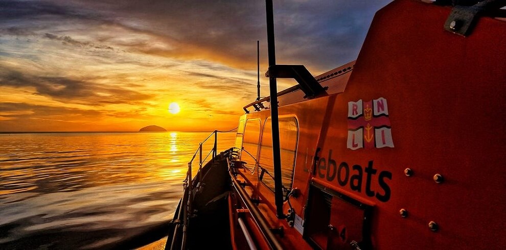 A picture of the RNLI Lifeboat out at sea during sunset.