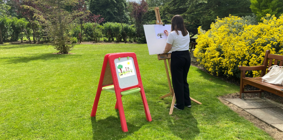 A person painting on an easel outside.
