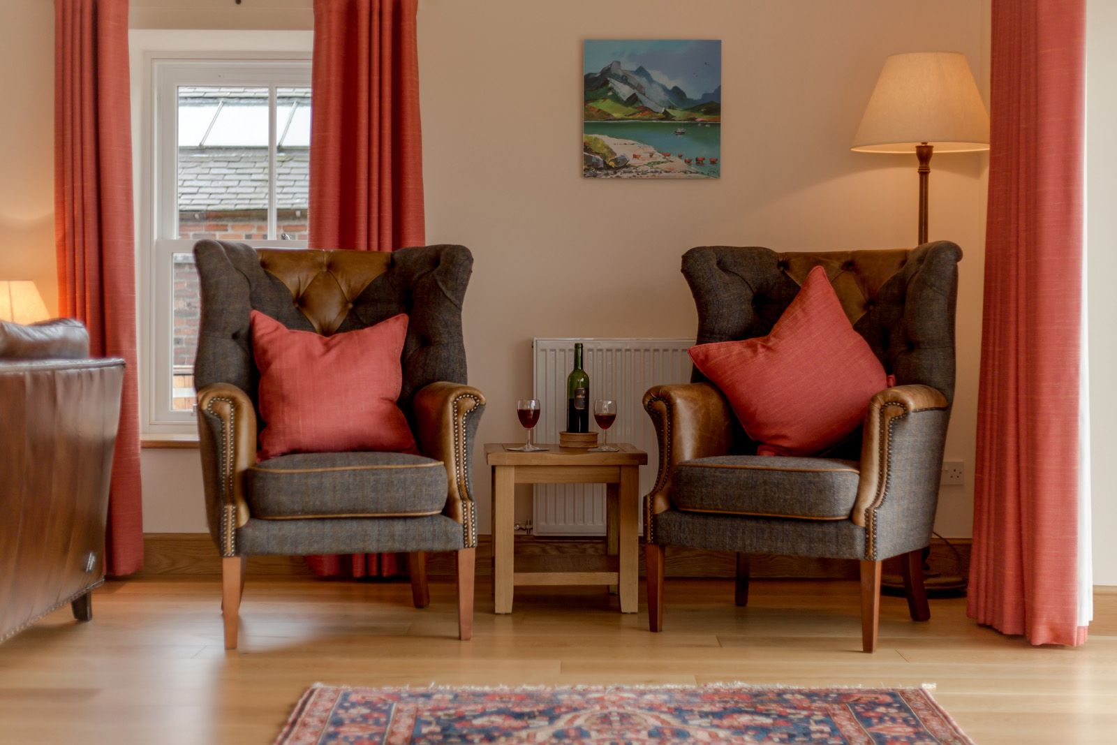 An image of two chairs with a table in between. There are wine glasses placed on the table.