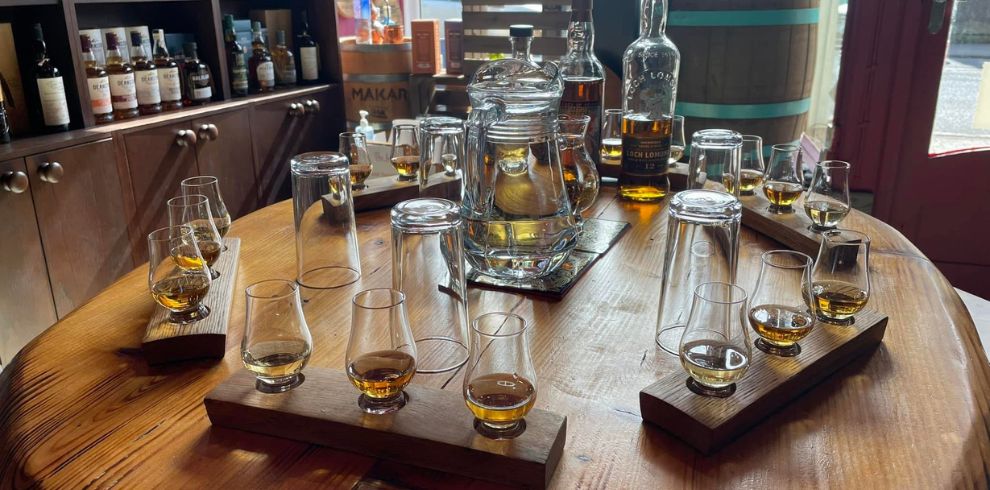An image of a wooden table with whiskey bottles and glasses displayed on it.