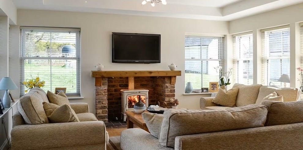 The lounge area of Yonderton House with a tv on the wall and a cosey fire burning below.