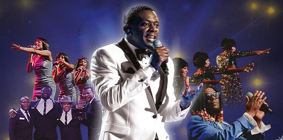 A promotional image for the stage show A Night to Remember: Motown Show, featuring a central performer in a white tuxedo holding a microphone, with groups of singers and musicians in the background. Female performers in silver and glittering dresses sing and dance, while male vocalists in suits and sunglasses add to the Motown vibe. The image evokes a lively and nostalgic tribute to classic Motown music