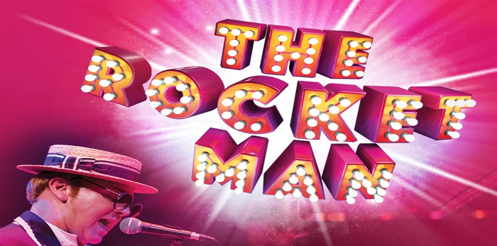 Promotional poster featuring the artist from The Rocket Man stage show, closely resembling Elton John and singing passionately. The title 'Rocket Man' is displayed at the top in a colourful, light bulb-style font, evoking a vibrant and energetic atmosphere