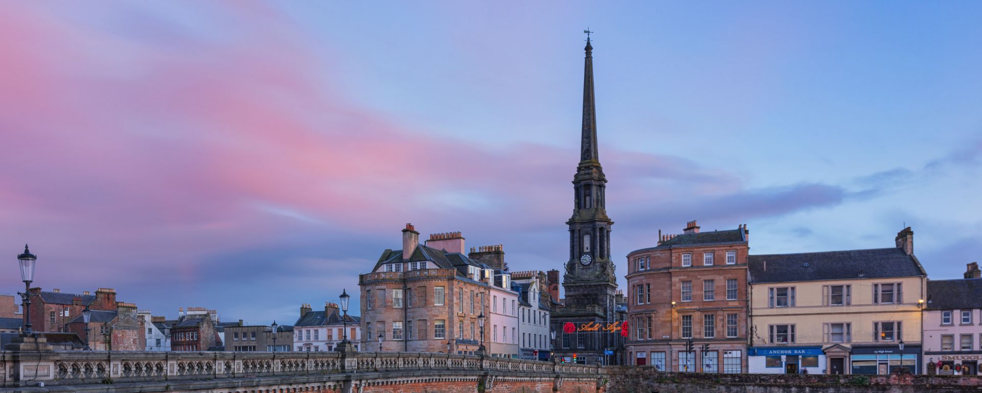 Stone bridge over river with Town hall spire in the distance.