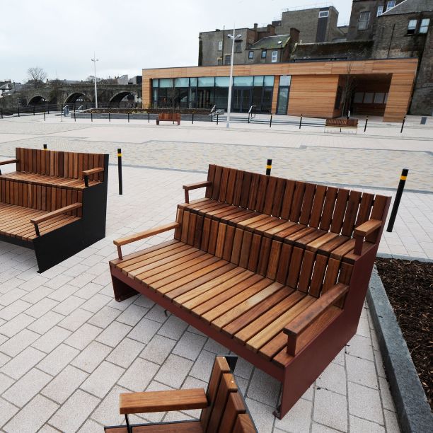 Wooden rectangular building and outdoor paved area with seatiing.