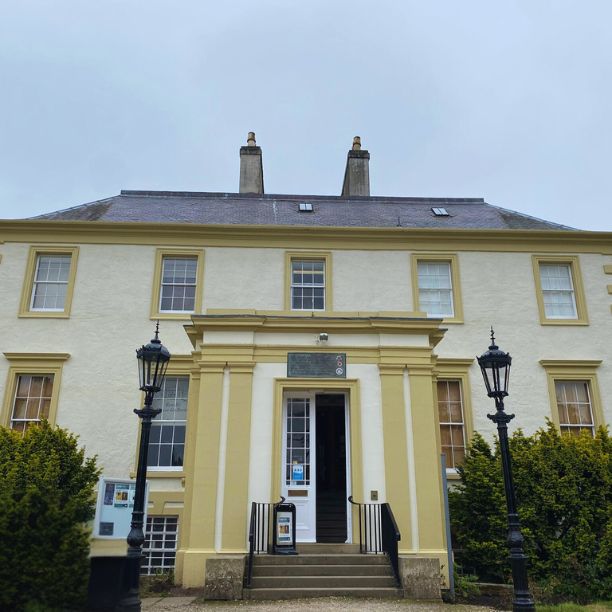 Exterior of large mansion house with open door.